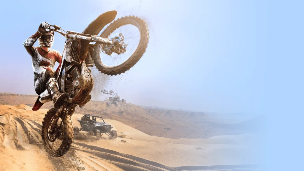 Ein Motocross-Fahrer hebt sein Motorrad in der Wüste auf das Hinterrad, während weitere Geländefahrzeuge folgen.