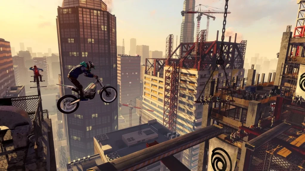 Ein Motorradfahrer springt in Trials Rising zwischen Hochhäusern über eine Baustelle.